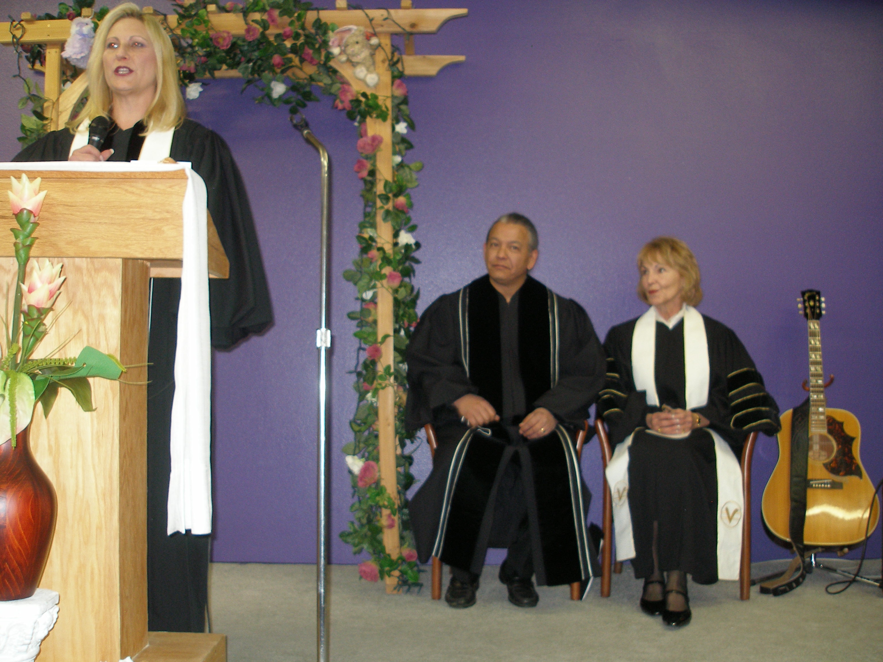 Rev. Lynn Tucker seated on stage with minister at Rev. S. Tucker's ordination