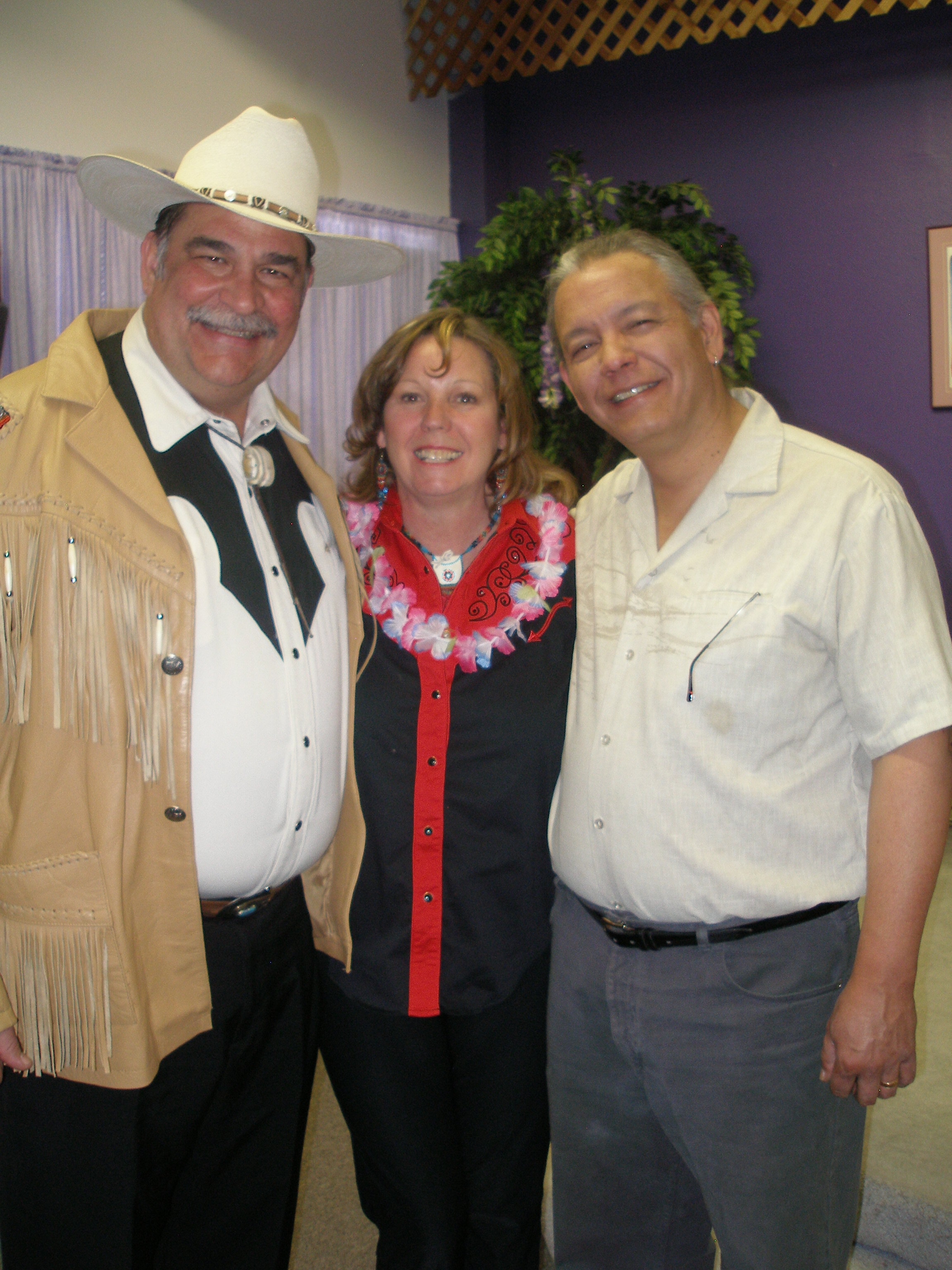 Three people in western attire with lei at Oasis CSL event