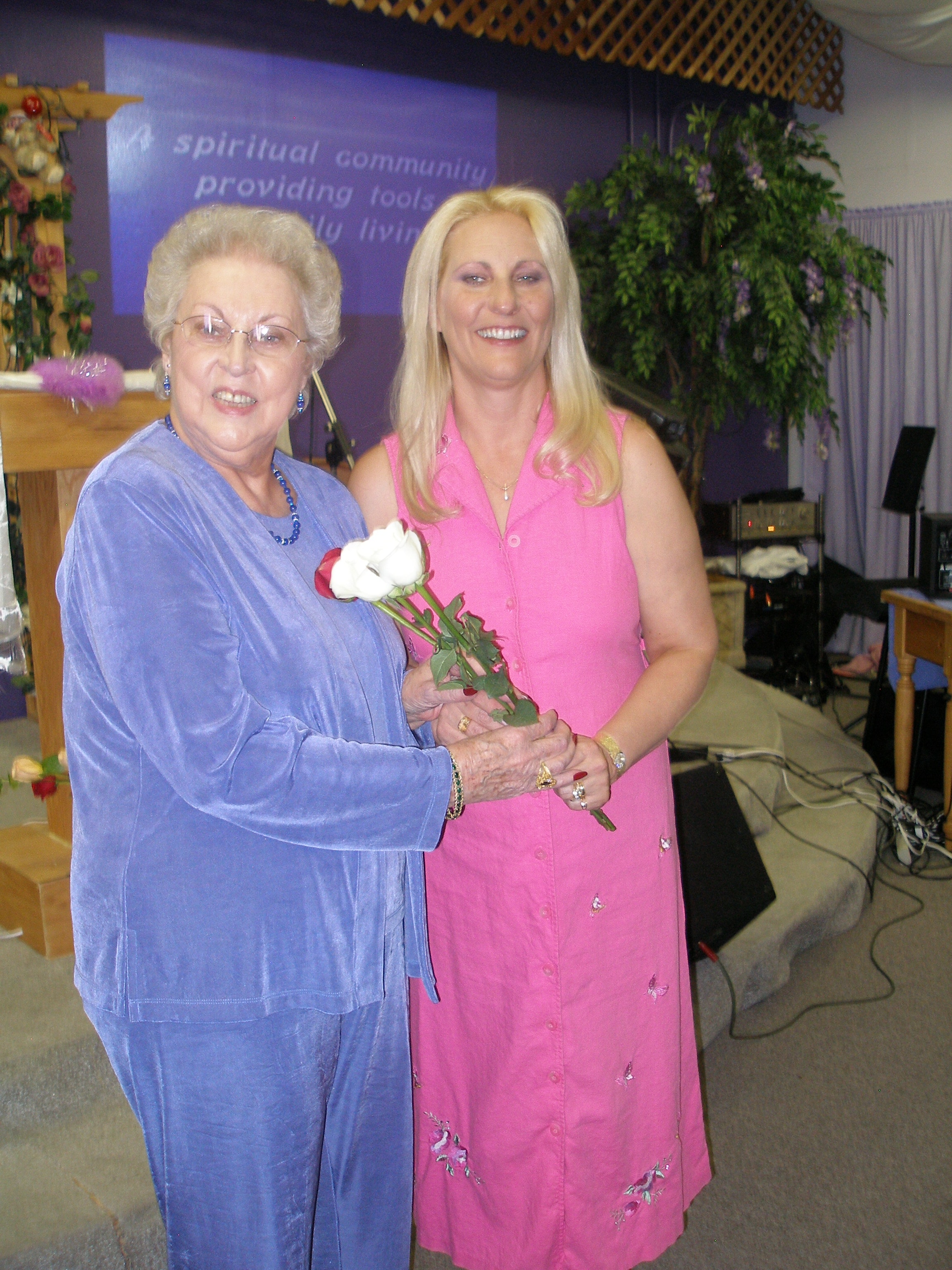 Two women holding roses together at the Oasis CSL altar