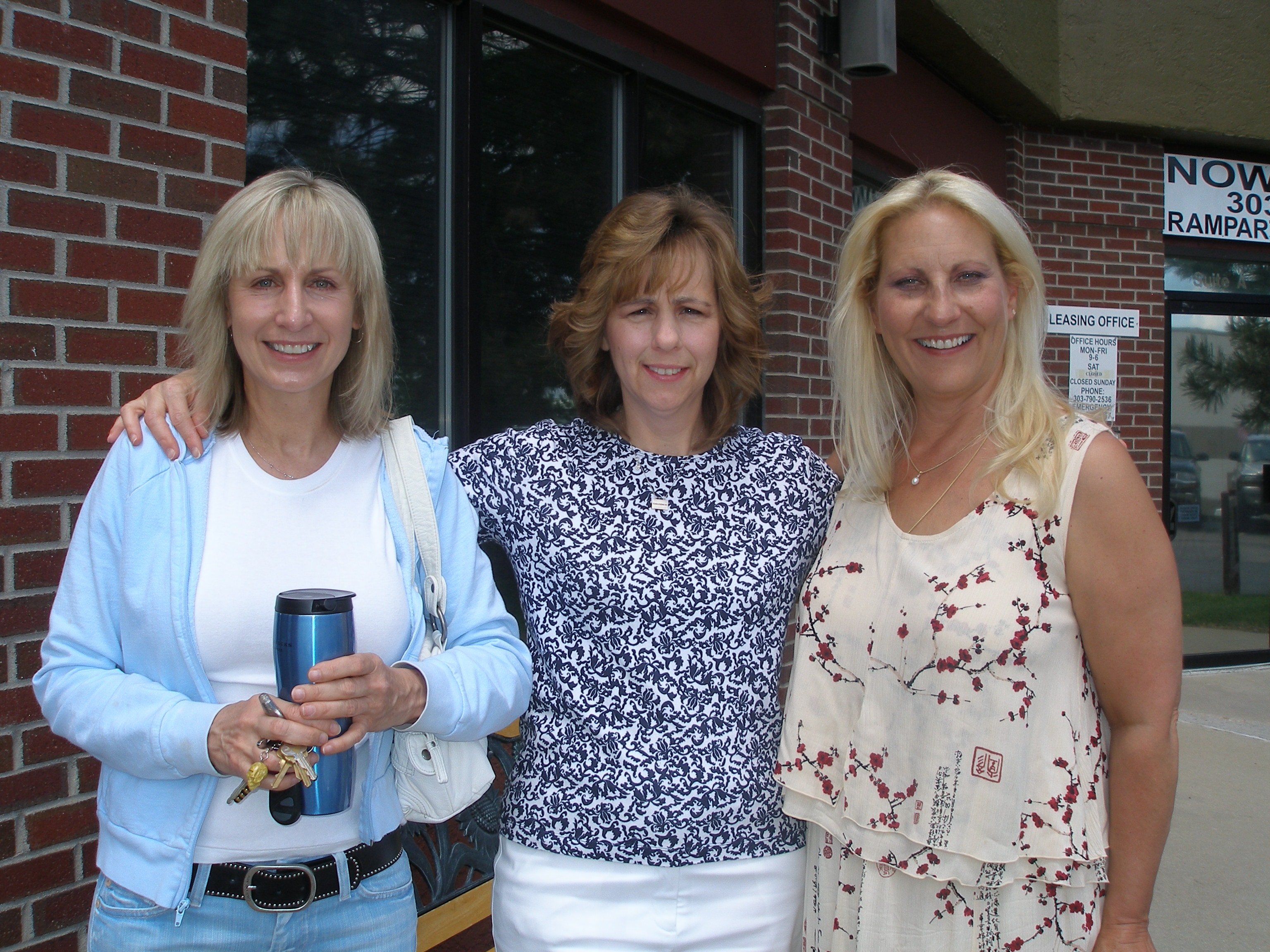 Three women smiling together outside the Oasis CSL building