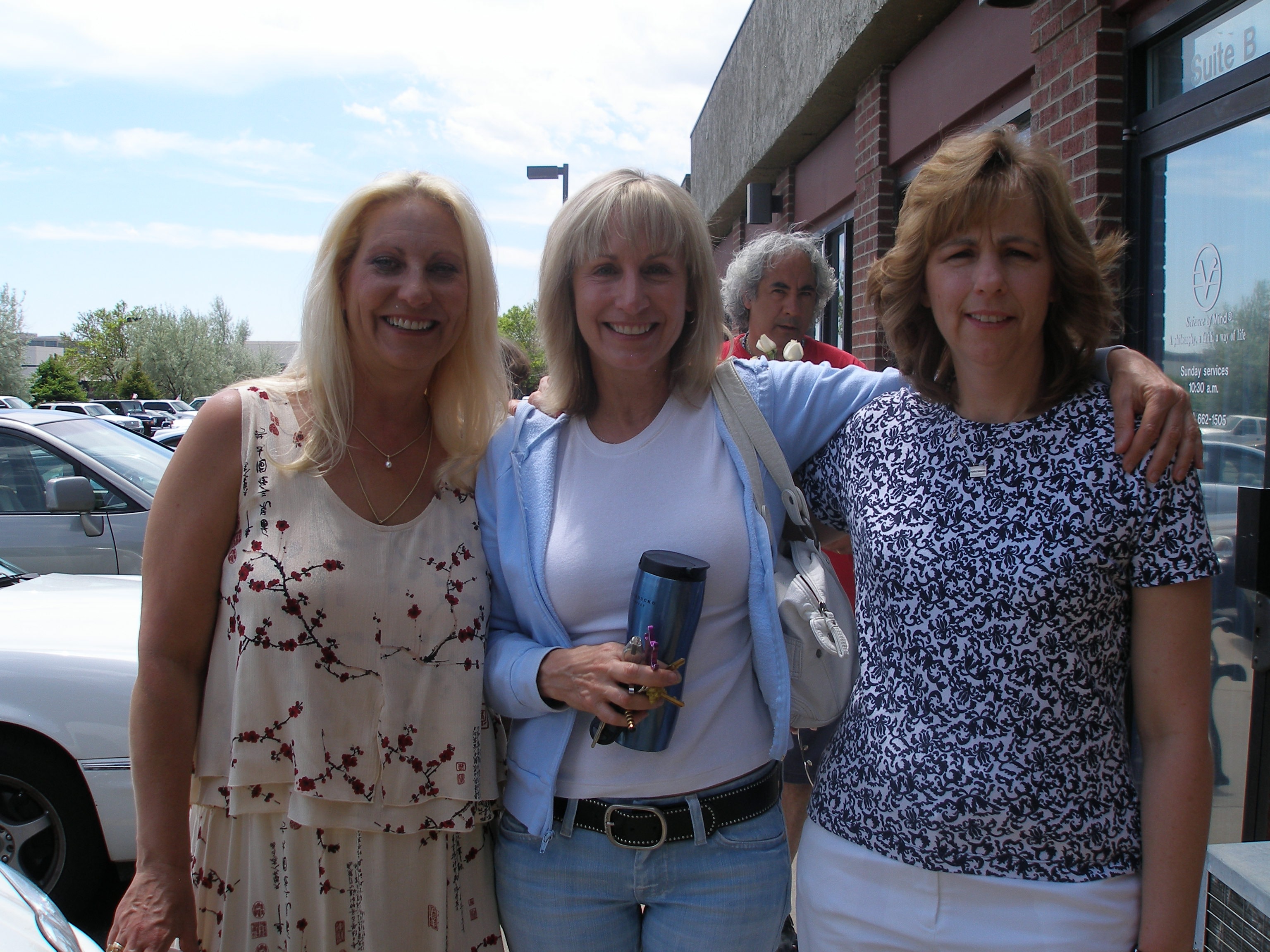 Three women smiling together outside the Oasis CSL building
