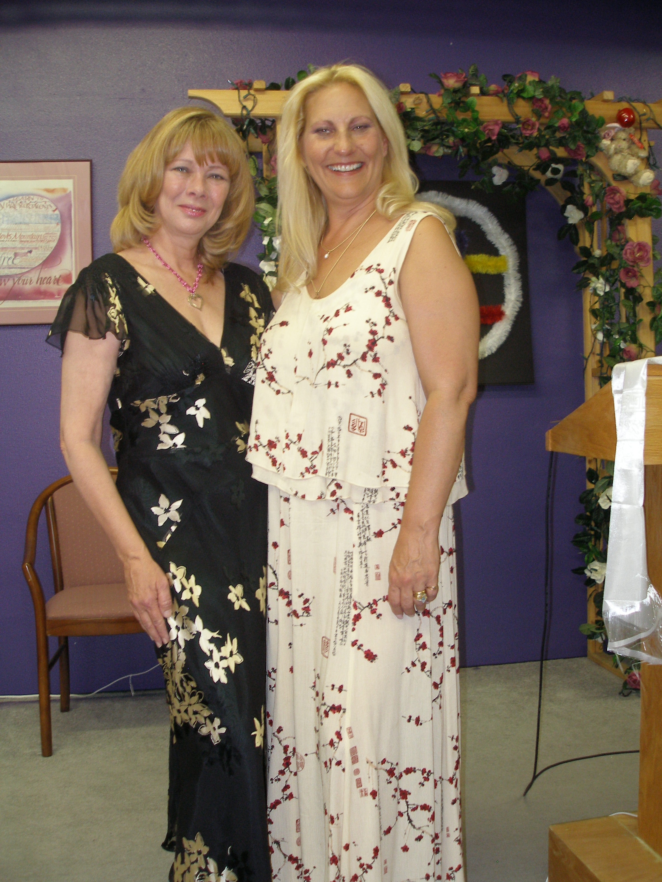 Two women posing together in the Oasis CSL sanctuary with floral arch