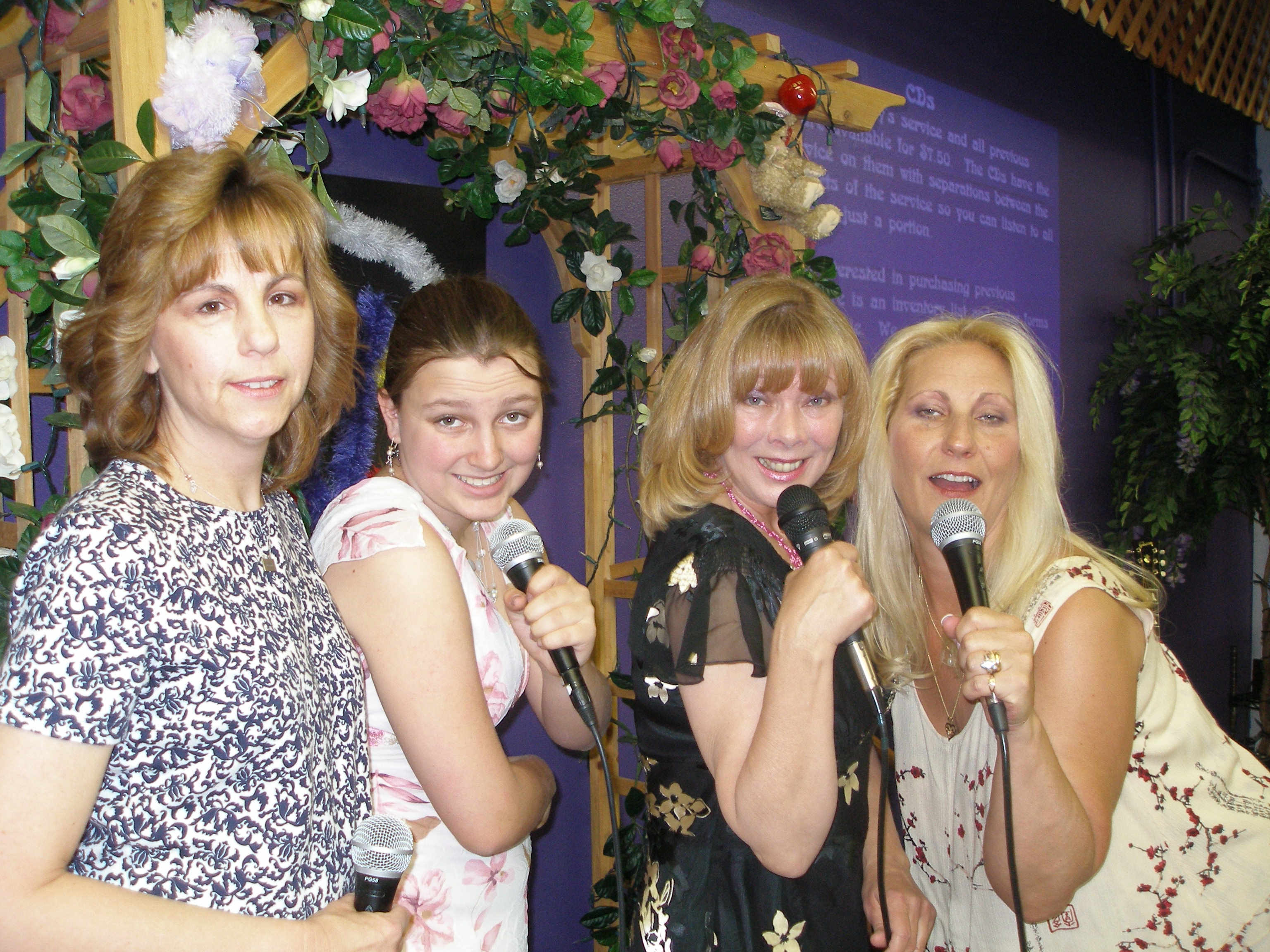 Four women laughing and singing with microphones at Oasis CSL event