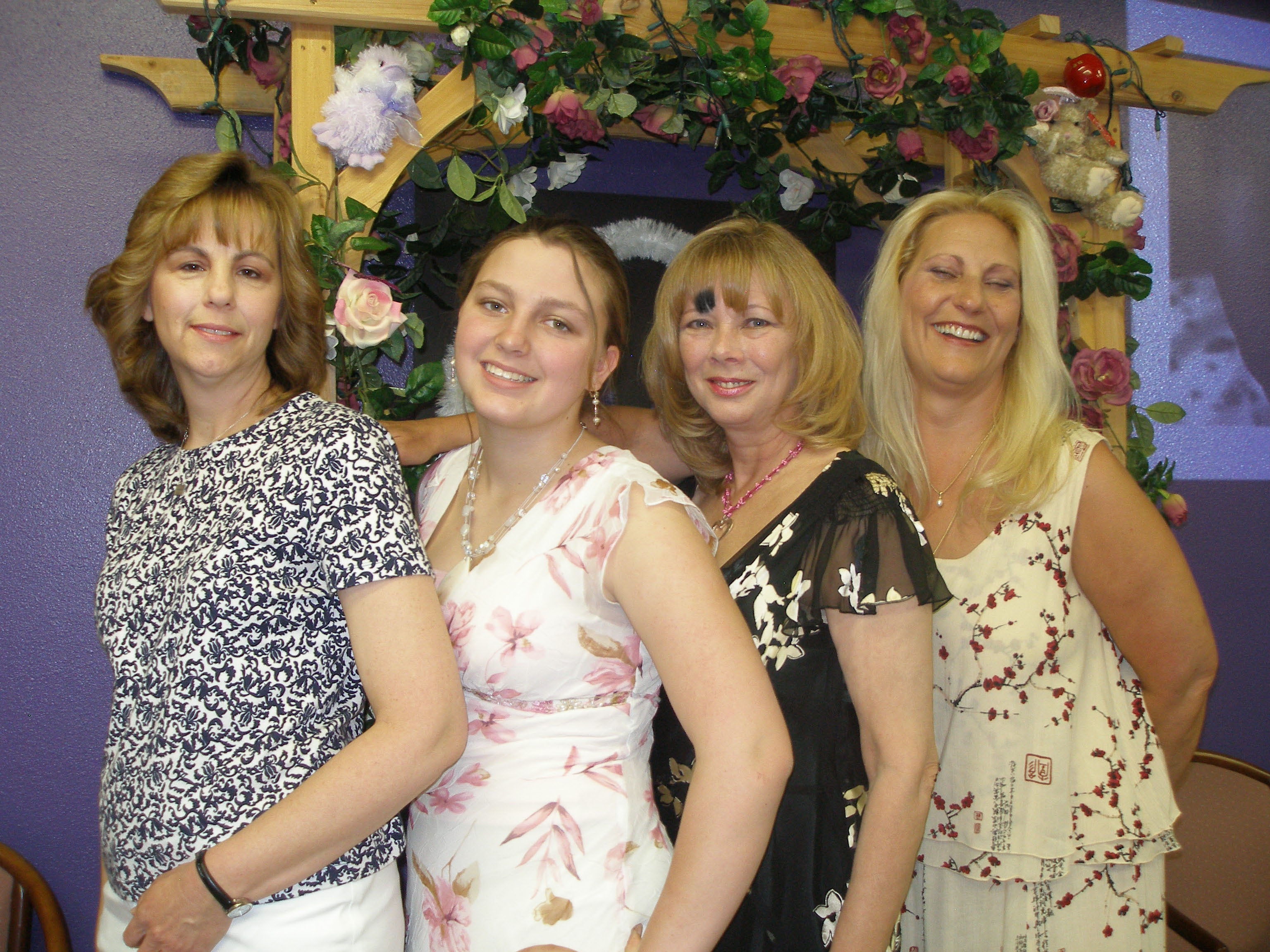 Four women posing together in front of the Oasis CSL floral arch