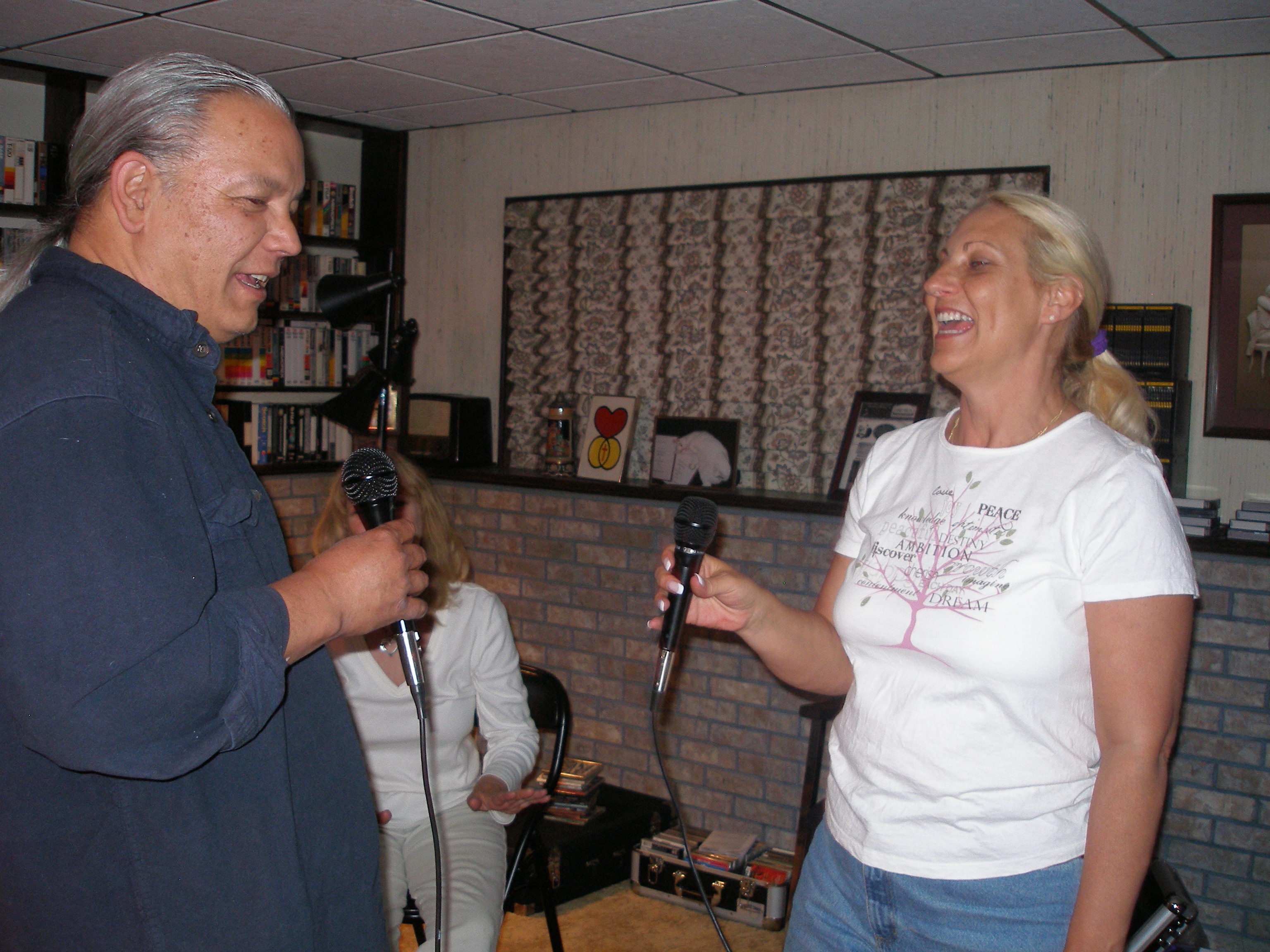 Man and woman laughing together while singing with microphones at Oasis CSL