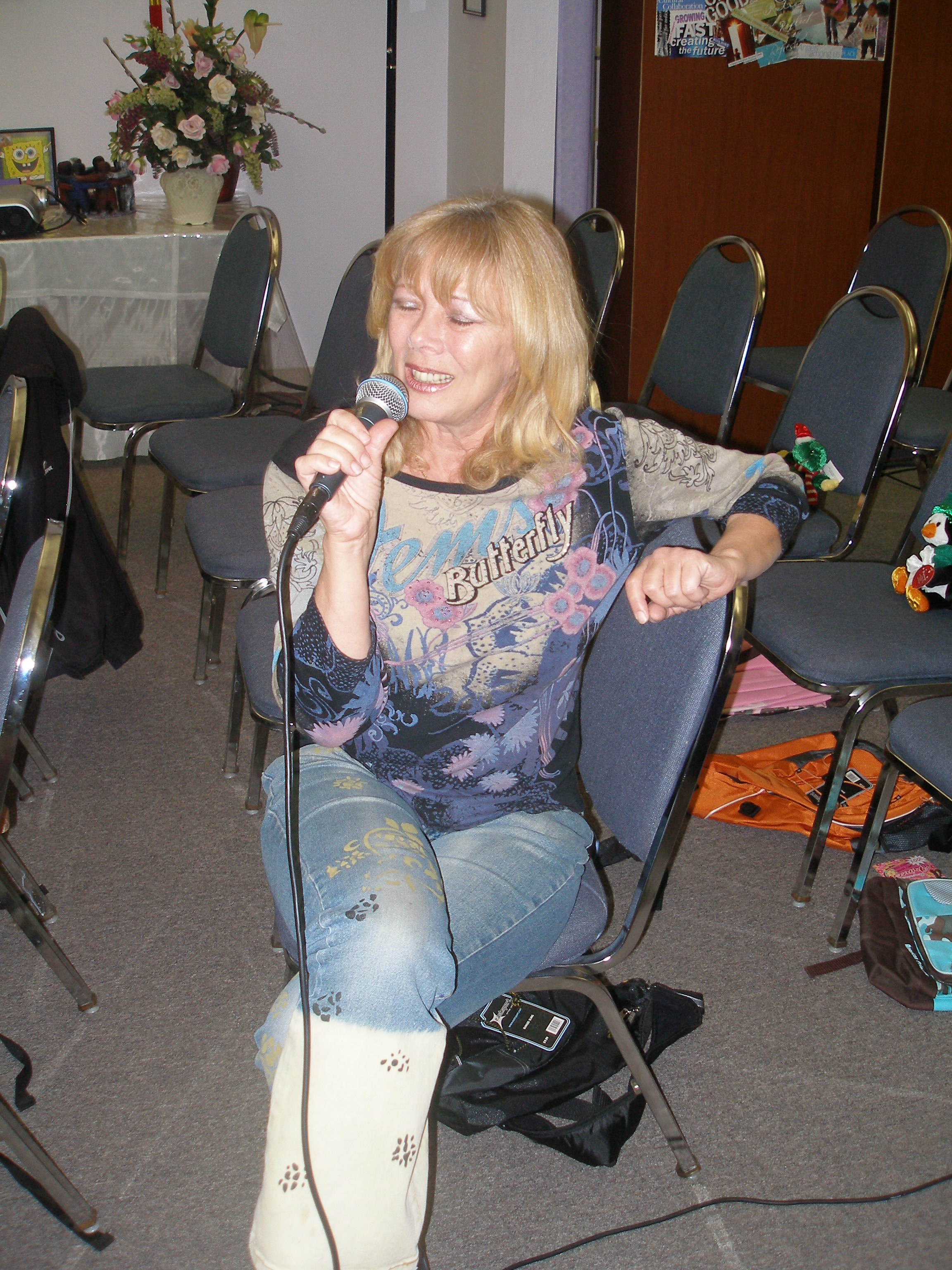 Woman laughing joyfully with microphone at Oasis CSL community event