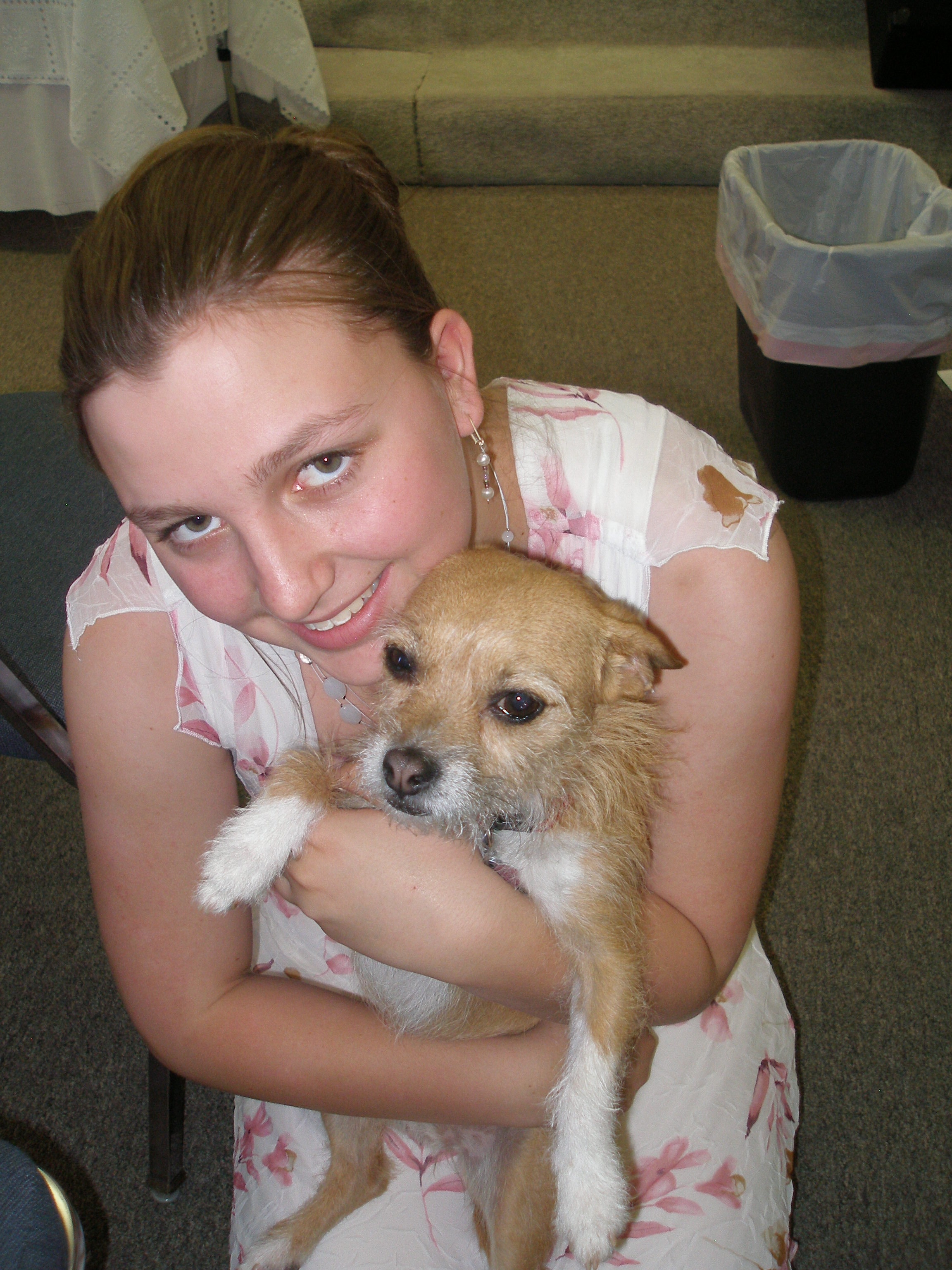 Young woman smiling while holding a small dog at Oasis CSL