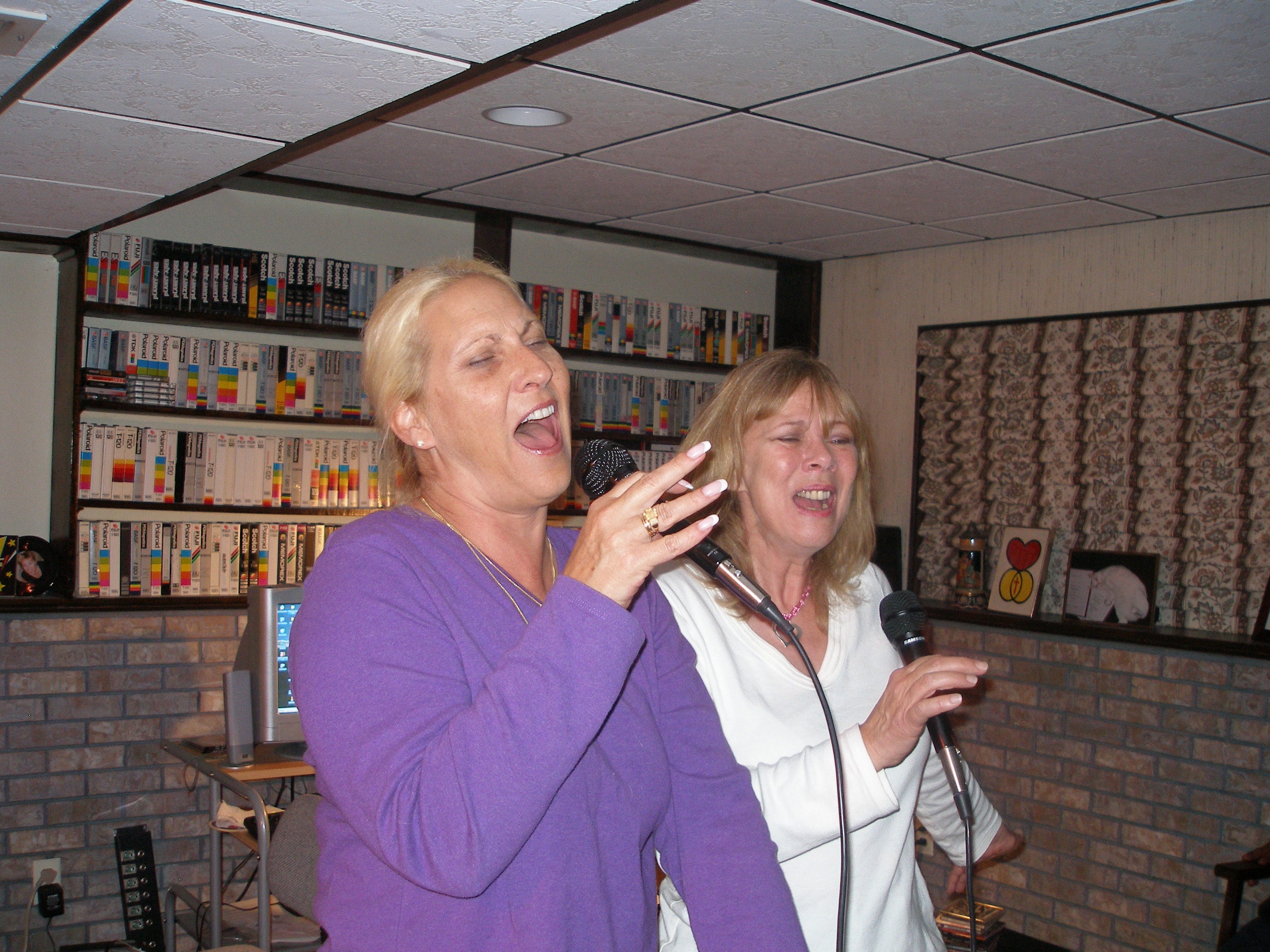 Two women singing passionately together with microphones at Oasis CSL