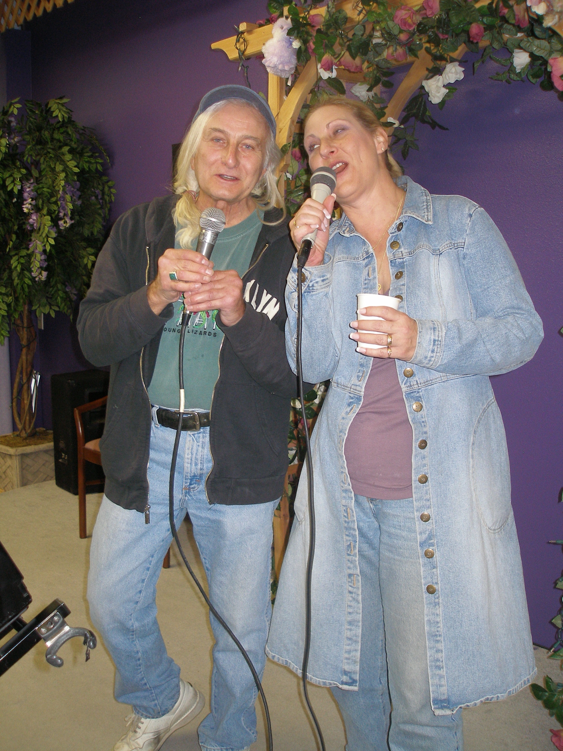 Two people singing together at Oasis CSL event with floral arch backdrop
