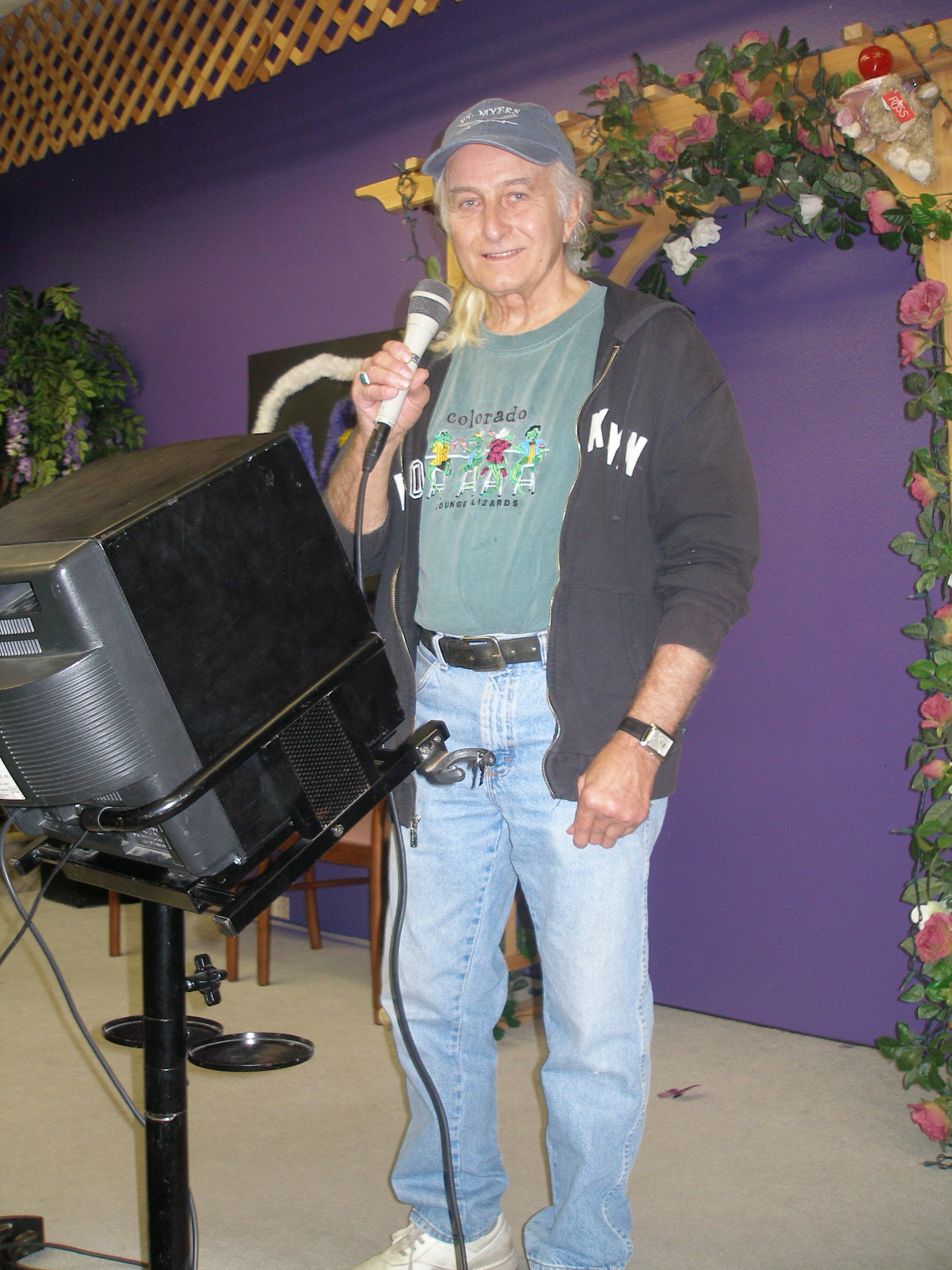 Man singing solo at microphone by the floral arch at Oasis CSL