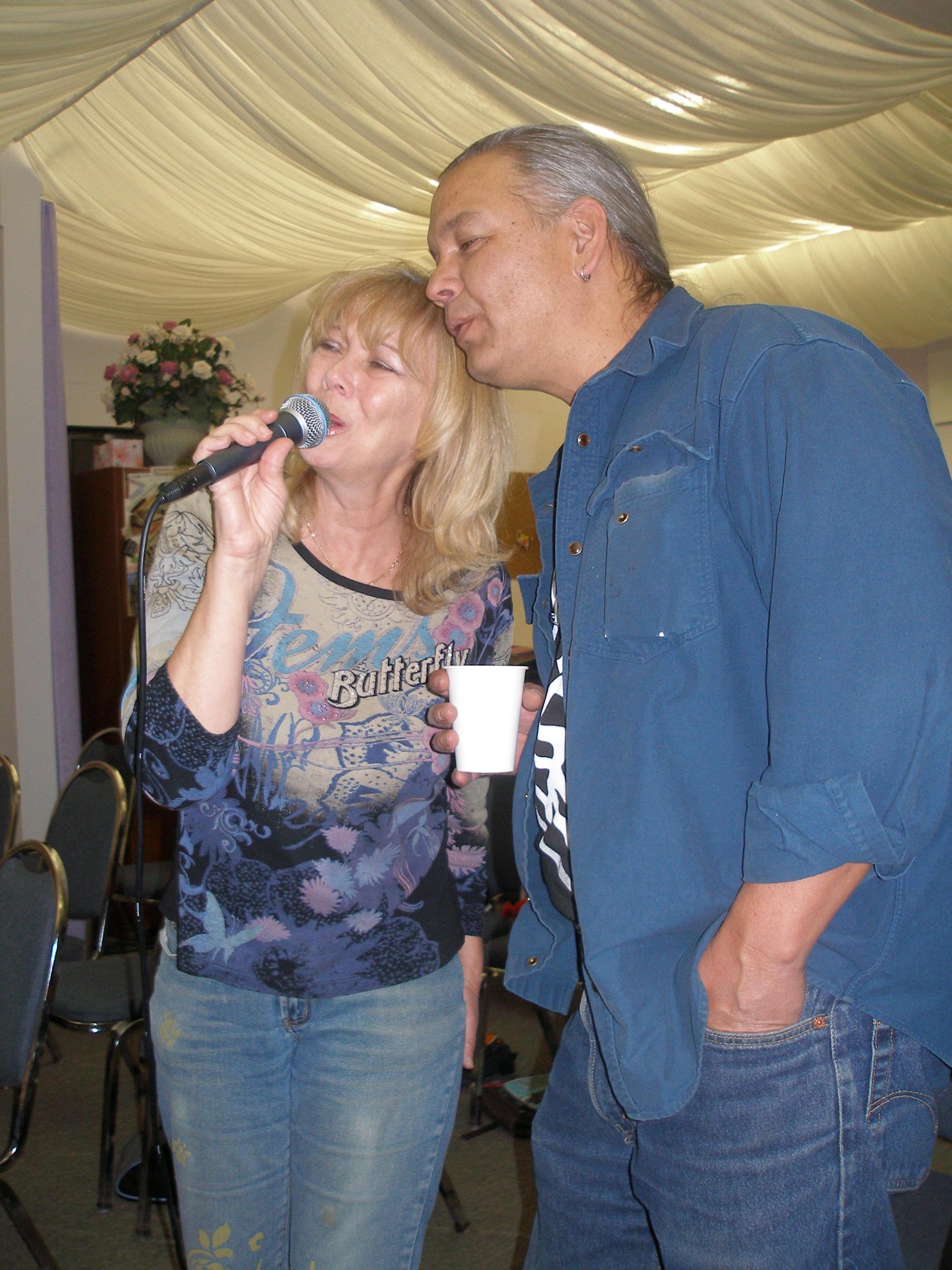 Man and woman sharing a microphone and laughing at Oasis CSL event