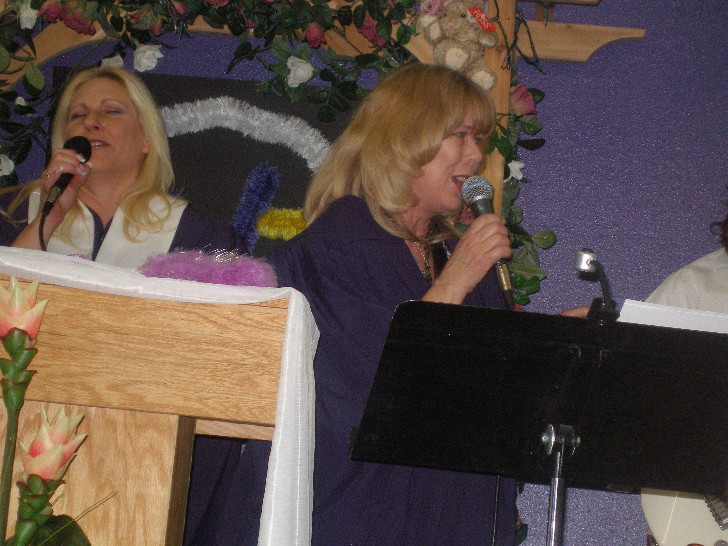 Two women singing at microphones at Rev. S. Tucker's ordination