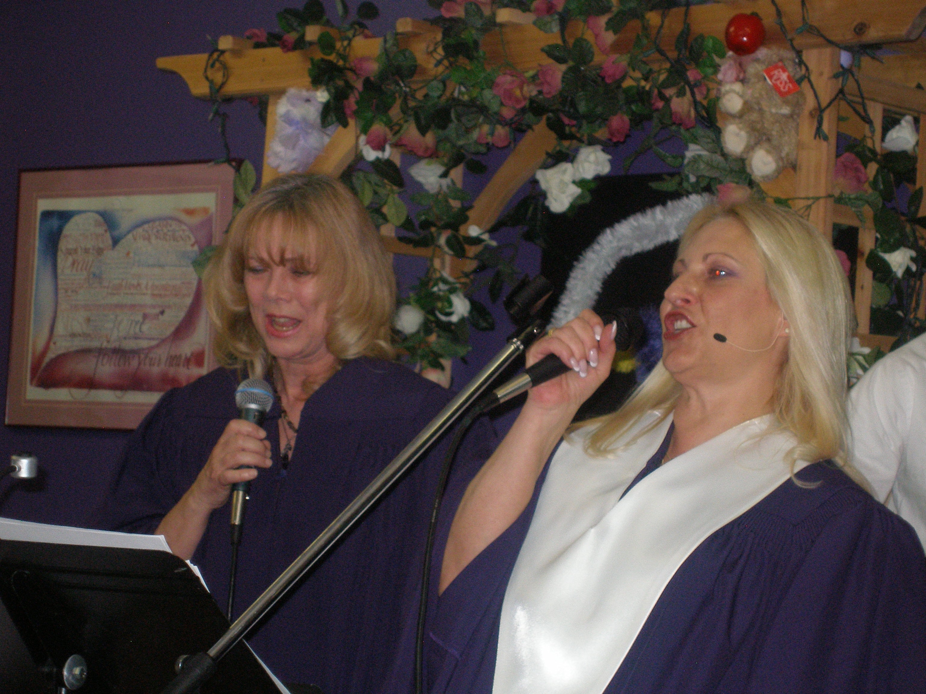 Two women in purple robes singing together at Rev. S. Tucker's ordination