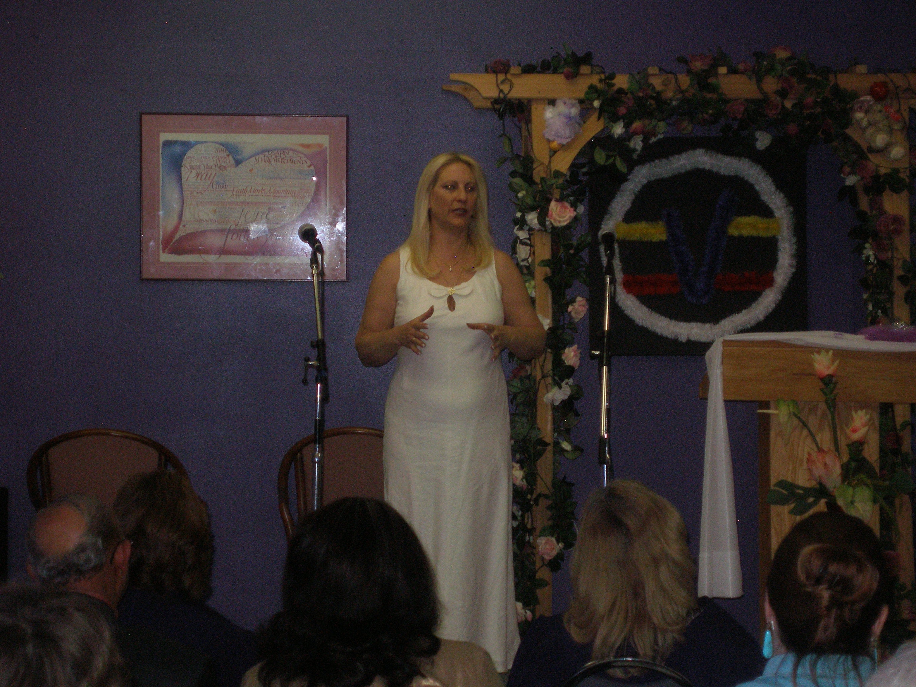Rev. S. Tucker in white dress speaking before congregation at ordination